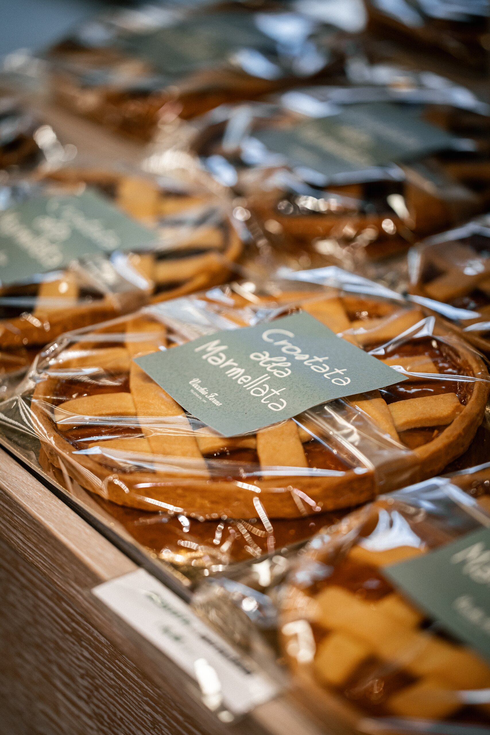 Crostata alla marmellata confezionata con etichetta color salvia nel carattere scritto a mano