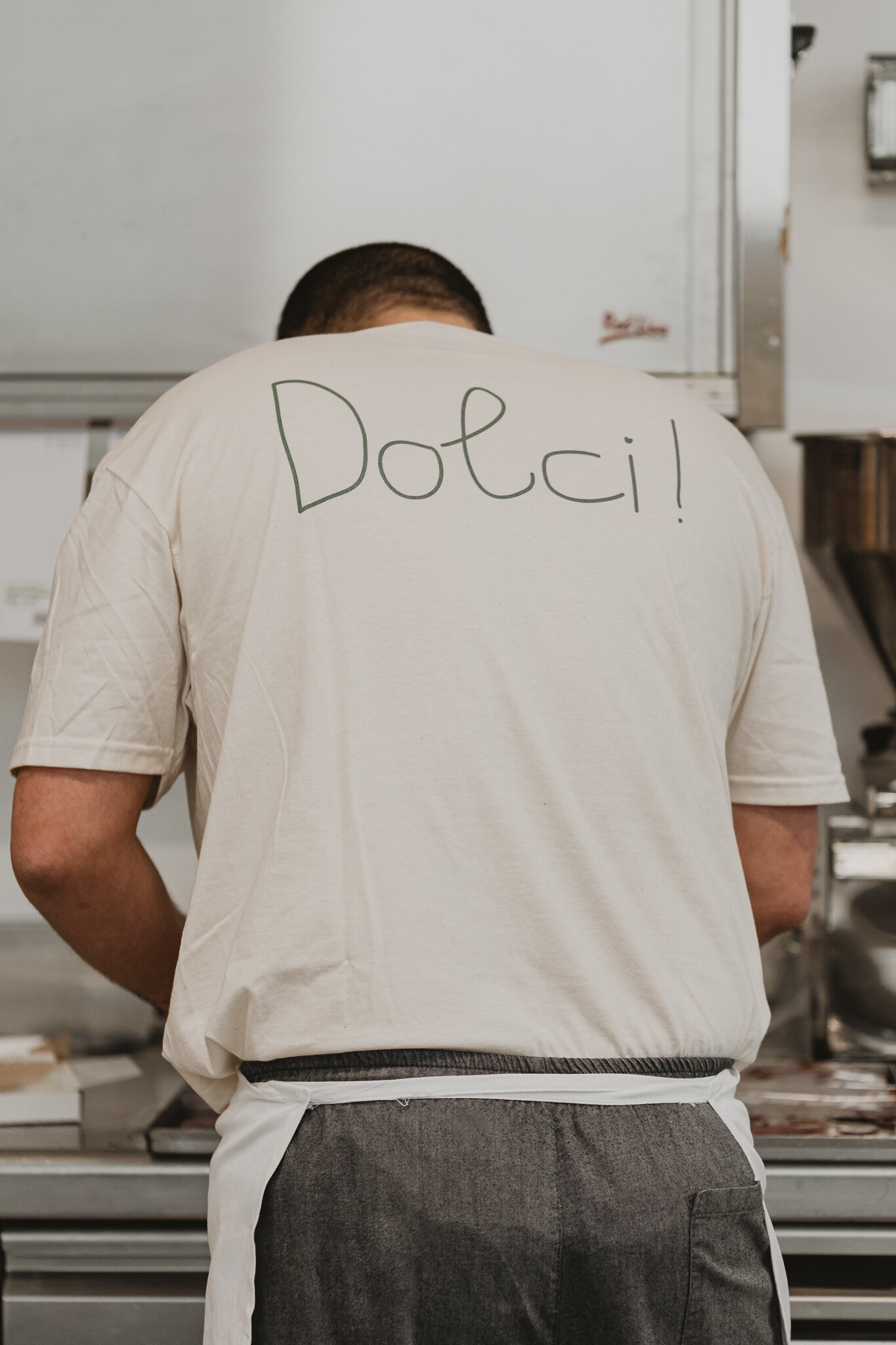 Pasticciere al lavoro nel laboratorio del Vecchio Forno con maglietta Dolci!