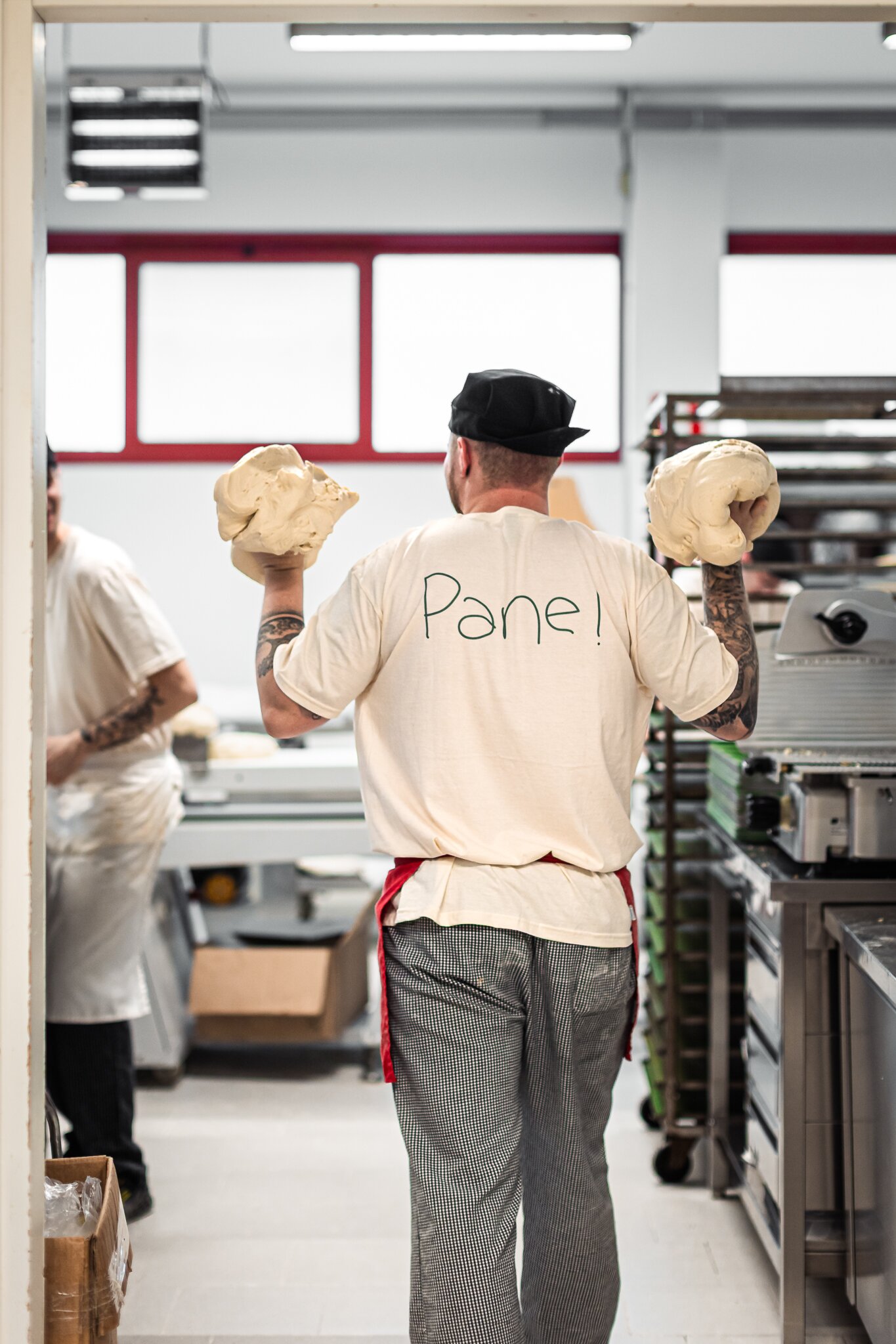 Panettiere nel laboratorio del Vecchio Forno con maglietta Pane!