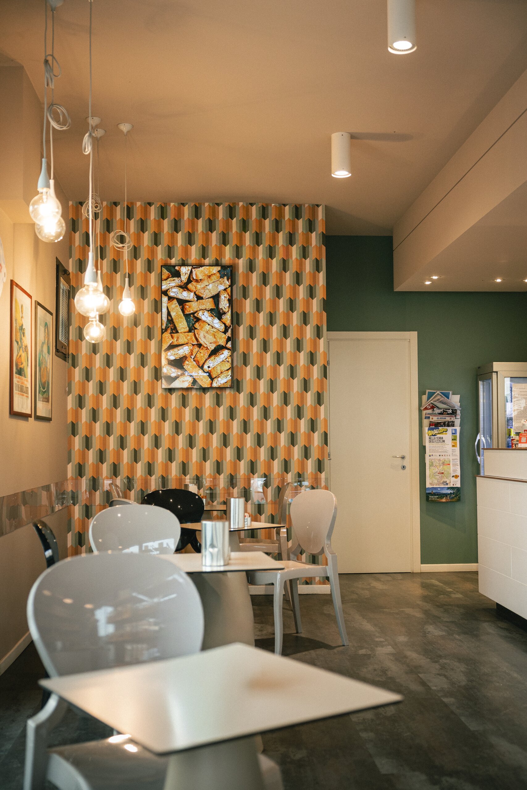 Sala caffetteria del Vecchio Forno con tavolini bianchi e parete a motivo geometrico